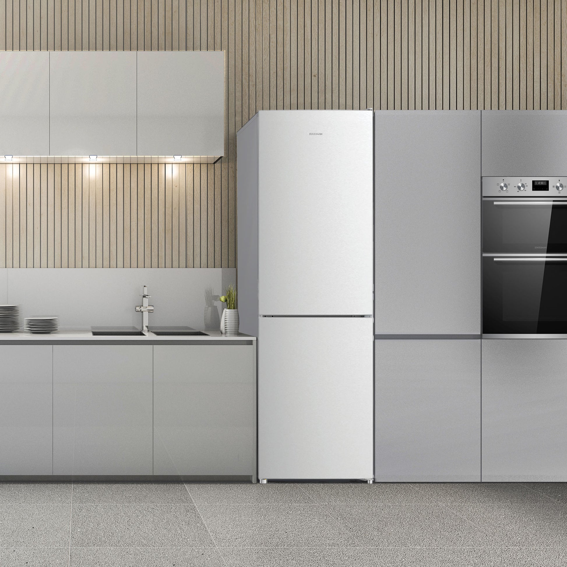 Modern kitchen with light gray cabinets, a Statesman v60/40 Low Frost Fridge Freezer in White by Statesman Appliances, built-in oven, sink, stovetop, and dishes on the counter. The wall features vertical wooden slats and under-cabinet lighting, while adjustable shelving ensures flexible storage options.