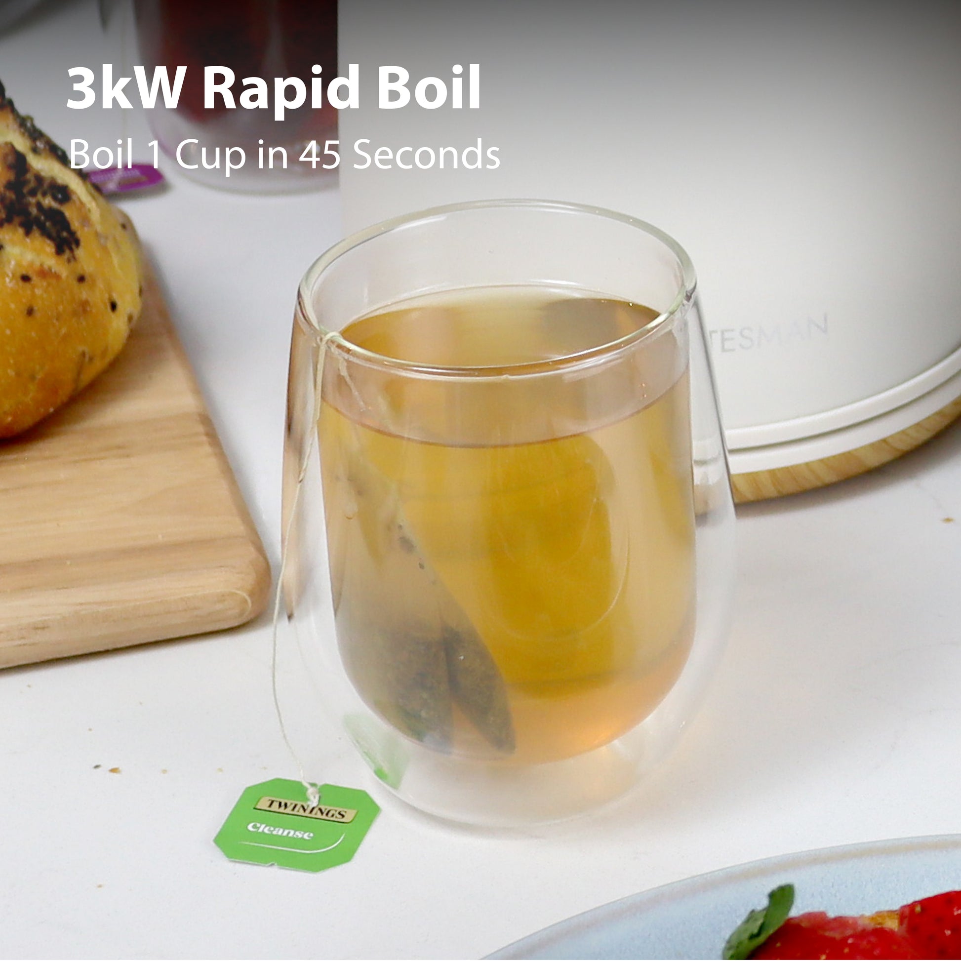 A clear glass cup with a tea bag and green label sits beside a bread roll and the Statesman Appliances Statesman 1.7L Scandi Kettle. Text: 3kW Rapid Boil – Boil 1 Cup in 45 Seconds. Cordless base for added convenience.