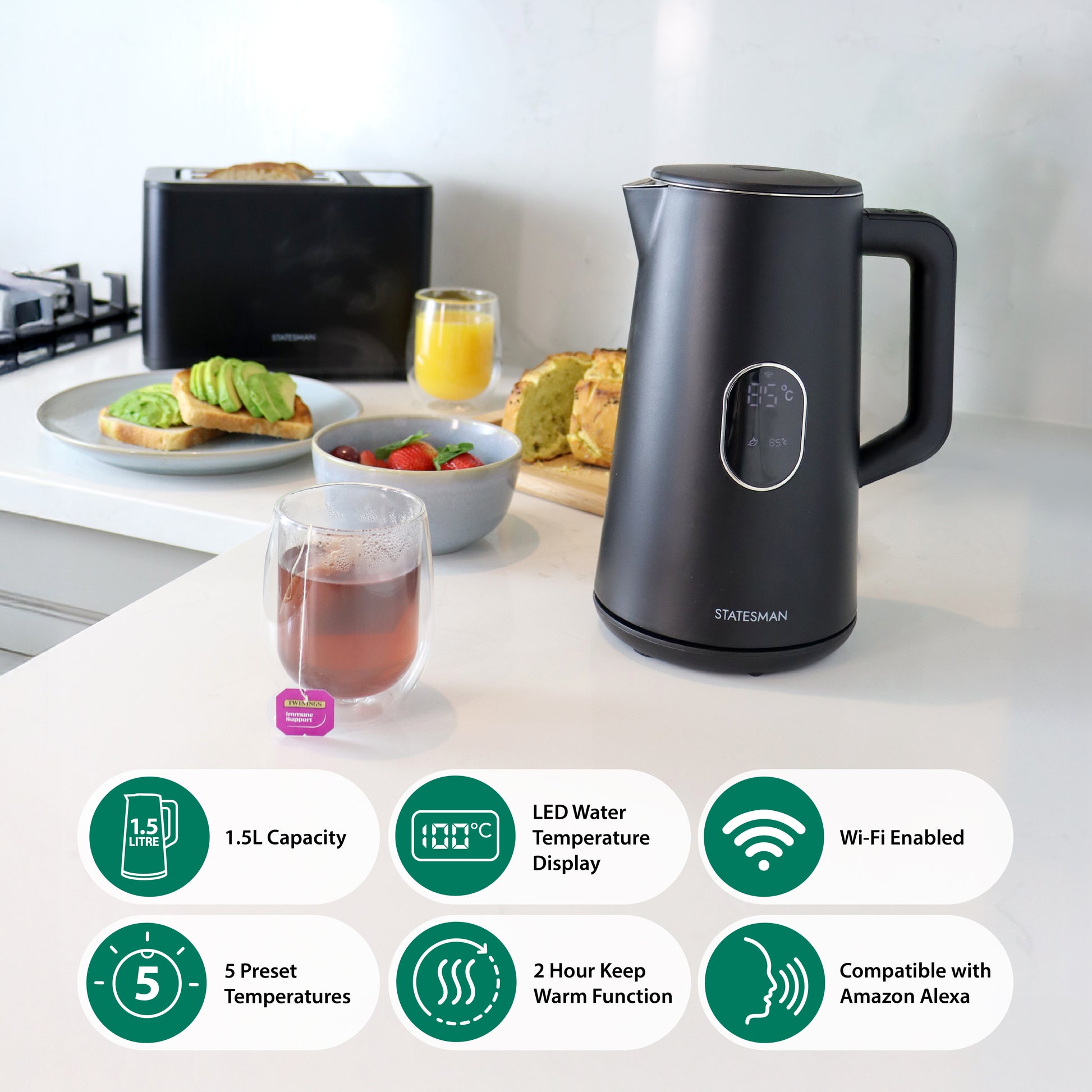 A Statesman Appliances 1.5L 1800W Smart Jug Kettle in black with temperature control and digital display sits on a kitchen counter near tea, avocado toast, strawberries, and orange juice. Icons show capacity, presets, and Alexa compatibility.