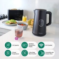 A Statesman Appliances 1.5L 1800W Smart Jug Kettle in black with temperature control and digital display sits on a kitchen counter near tea, avocado toast, strawberries, and orange juice. Icons show capacity, presets, and Alexa compatibility.