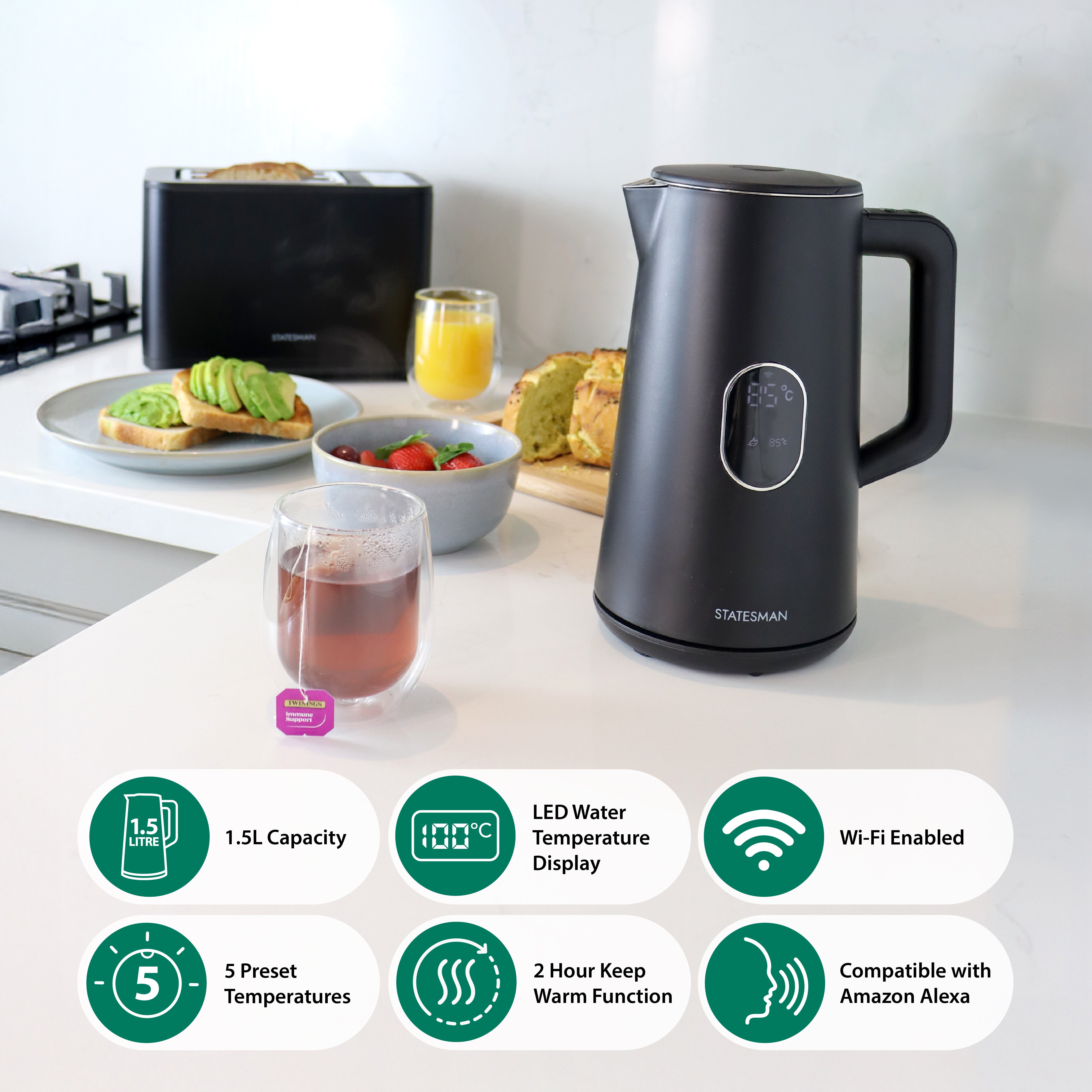 A Statesman Appliances 1.5L 1800W Smart Jug Kettle in black with temperature control and digital display sits on a kitchen counter near tea, avocado toast, strawberries, and orange juice. Icons show capacity, presets, and Alexa compatibility.