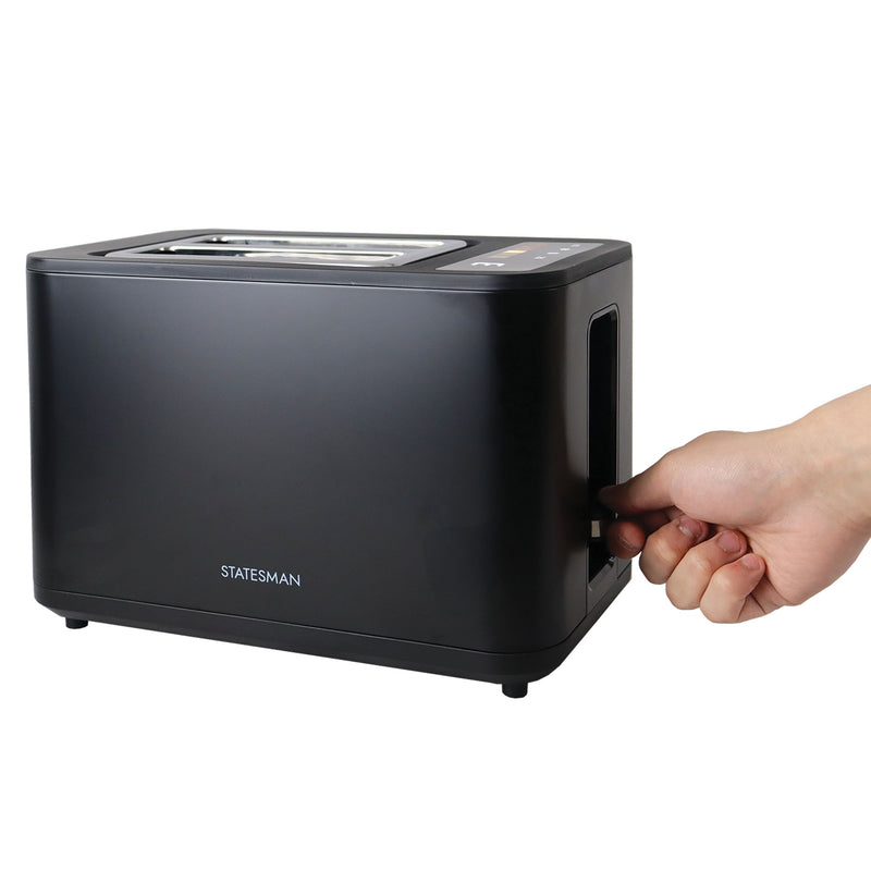 A hand pushes down the lever on a black Statesman Appliances 900W 2 Slice Digital Toaster, set against a plain white background.