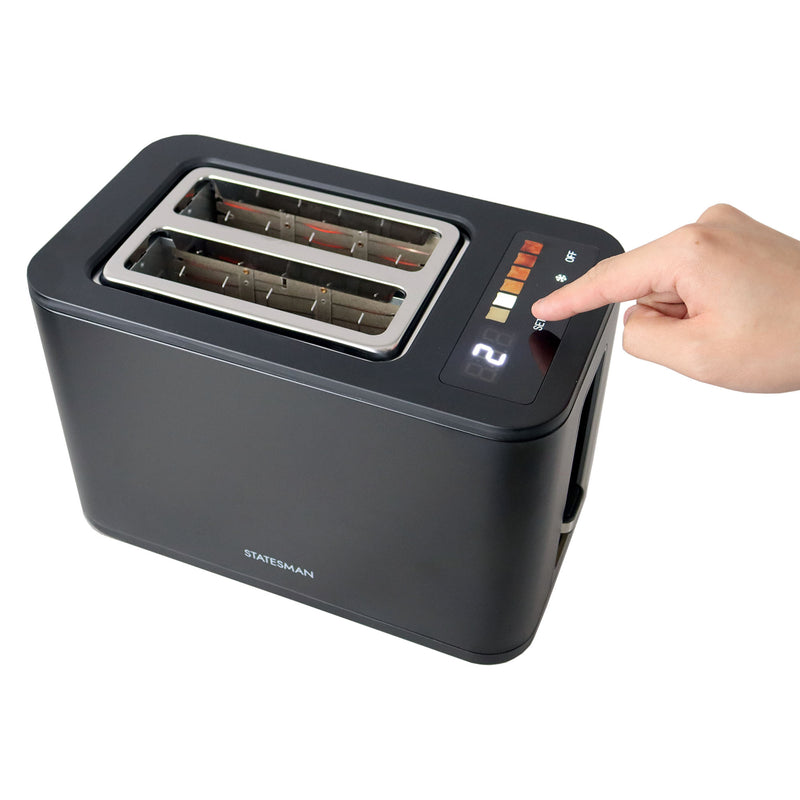 A hand presses a digital button on a black Statesman Appliances 900W 2 Slice Digital Toaster, featuring wide slots and an LED display with toast settings.