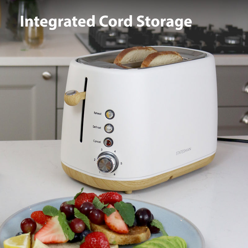 A Statesman Appliances 900W 2 Slice Scandi Toaster in white sits on a kitchen counter beneath the text "Integrated Cord Storage," with a plate of fruit and pancakes in the foreground.