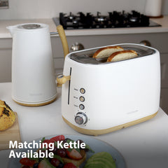 A Statesman Appliances 900W 2 Slice Scandi Toaster with bread and a matching white electric kettle sit on the counter. Text reads "Matching Kettle Available." A stove and food items are in the background.