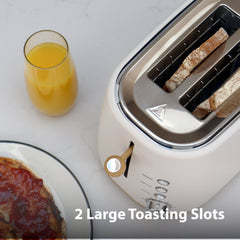 The Statesman 900W 2 Slice Scandi Toaster by Statesman Appliances sits on a countertop with its 2 large toasting slots, next to a glass of orange juice and a plate with toast and jam. Text reads: 2 Large Toasting Slots.