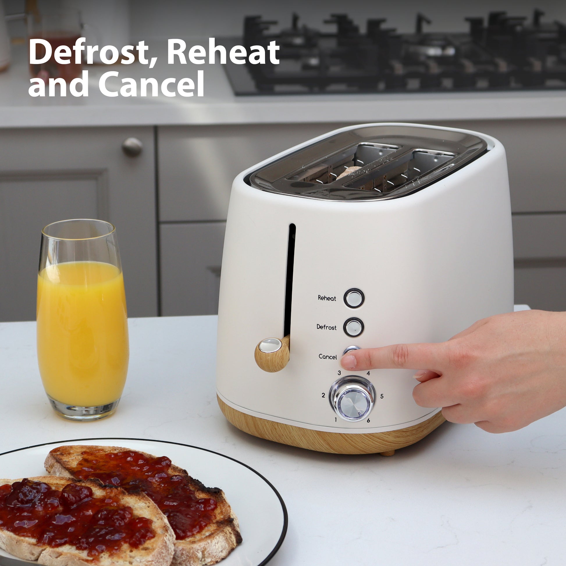 A hand presses a button on the white Statesman 900W 2 Slice Scandi Toaster from Statesman Appliances, labeled Reheat, Defrost, and Cancel. Nearby are a glass of orange juice and two slices of jam toast. "Defrost, Reheat and Cancel" tops the scene.
